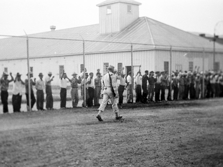 フェンスの中から外を見る一世の収容者達（1943年） モンタナ州、フォートミズーラの司法省抑留所 Courtesy of the University of Washington Libraries 