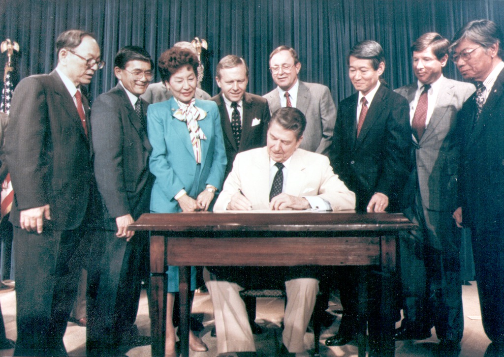 1988年市民自由法に署名するレーガン大統領　（1988年、ワシントン　DC）